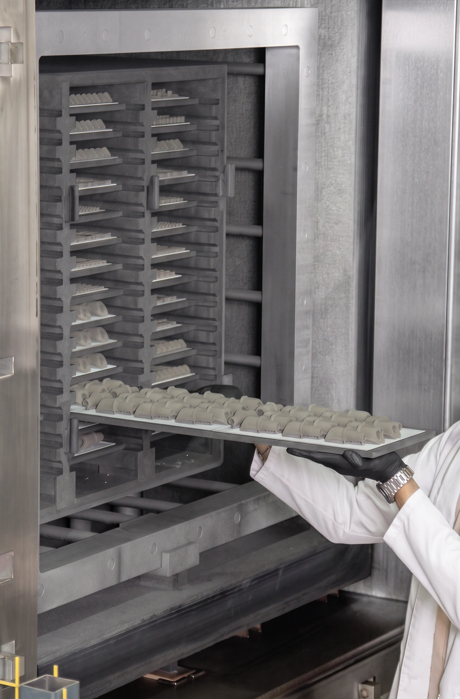 Modern bir MIM üretim hattında hassas metal parçalar üretiliyor; makineler, kalıplar ve metal bileşenler ön planda, arka planda endüstriyel fabrika ortamı ve profesyonel üretim düzeni görülüyor. Görünüm kontrollü, temiz ve yüksek doğruluk odaklıdır.